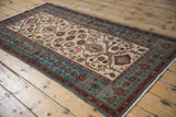 Distressed vintage Hamadan runner viewed from an angle showing its lattice and floral design.