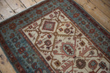 Angled view of a distressed Hamadan rug showing its worn pile and geometric border.