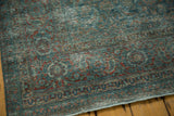 Vintage distressed Tabriz carpet corner, showcasing low pile and faded teal and red turtle border.