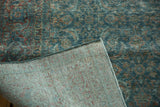 Folded corner of a distressed Tabriz carpet, revealing Herati pattern, woven foundation, and secured edge.