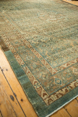 Close-up of distressed Malayer carpet corner, showing teal and brown geometric border.