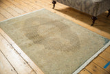 Distressed vintage Tabriz rug corner with worn beige and coffee brown Herati motif.