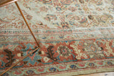 Wide terracotta border with oversized palmettes and sky blue leaves on the distressed Sultanabad rug.