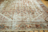 Distressed antique Sultanabad rug showing wide border with colorful palmettes and storied Herati texture.