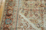 Angled view of the distressed Sultanabad carpet, showing hard wear, exposed foundation, and wide terracotta border.