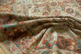 Antique Sultanabad rug's worn texture, displaying faded Herati motifs in terracotta and blue.