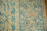 Distressed Kerman rug with intricate ivory, pale gold, and sky blue floral motif.