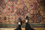 Antique Persian Kerman carpet's cochineal red field, sprawling floral palmettes, and patterned border.