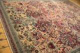 Antique Kerman rug's intricate floral palmettes with cochineal red, ivory, and navy blue border.