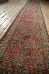 Angled perspective down the length of a distressed vintage Malayer runner with boteh designs.