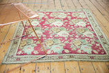 Corner of an Armenian Karabagh rug showing raspberry rose bouquet field and starburst border.