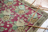 Antique Karabagh rug detail: hand-knotted raspberry rose bouquets and starburst border design.
