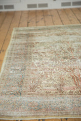 Distressed corner of vintage Persian Isfahan rug with worn pale yellow silk and blue patterns.
