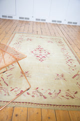 Scalloped trefoil medallion and floral motifs in raspberry red on the ivory Oushak rug.