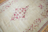 Vintage Oushak rug corner featuring raspberry red serrated leaf border and ivory floral field.