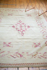 Vintage Turkish Oushak rug, raspberry red scalloped medallion on an ivory field with floral motifs.
