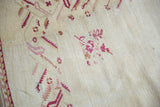 Ivory Oushak rug field with textured pile, raspberry floral motifs, and serrated border.