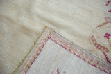 Hand-knotted foundation of a Vintage Oushak rug, with ivory field and raspberry border.