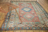 Decorative corner of distressed Caucasian rug, madder red field with starbursts and sky blue borders.