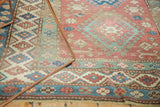 Distressed vintage Caucasian rug with geometric border in red, sky blue, and sand tones.