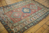 Distressed vintage Caucasian rug's geometric border with hook and latch motifs in blue and red.