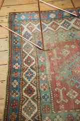 Distressed vintage Caucasian rug border, with geometric patterns, madder red, sky blue, beige, and worn fringe.