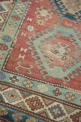 Distressed vintage Caucasian rug shows red, oxidized copper green hook and latch motifs.