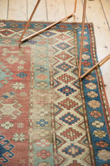 Distressed geometric patterns of a vintage Caucasian rug in red, sky blue, oxidized green.