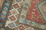 Distressed Caucasian rug detail: madder red field, playful pinwheel and geometric motifs.