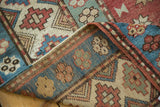 Distressed geometric motifs in sky blue, madder red, and beige on a vintage Caucasian rug pile.