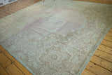 Distressed Kerman carpet displaying ornate Rococo floral patterns and faded blush, seafoam tones.