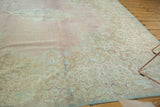 Faded floral motifs and secured edge of a distressed Kerman square carpet.