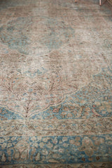 Distressed vintage Tabriz carpet showing faded ivory, beige, and powder blue scrolling vinery.