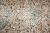 Distressed pile detail of vintage Tabriz with faded scrolling vinery and pale blue floral motifs.
