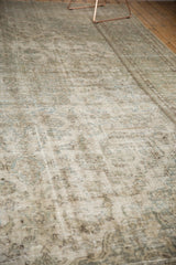 Angled view of a distressed vintage Meshed carpet with faded silver, ivory, seafoam floral patterns.