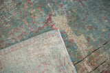 Corner of distressed Tabriz carpet revealing faded powder blue floral motifs and exposed foundation.