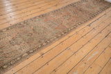 Distressed Lilihan runner's intact side selvage and floral vinery in dusty rose and coffee brown.