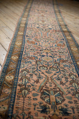 Angled view down the length of a vintage Lilihan runner showing its dusty rose field and blue borders.
