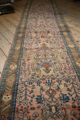 Low angle view down the length of a vintage Lilihan rug runner with a dusty rose field.