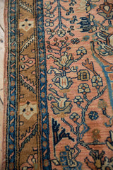 Intricate floral and vinery pattern on a hand-knotted Persian rug in dusty rose and bronze.