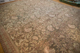 Angled view of a distressed Persian Malayer carpet showing its staggered boteh and scrolling vine pattern.