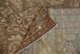 Folded corner of a distressed Malayer rug, displaying the patterned pile and woven foundation.