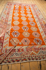 Tangerine orange vintage Turkish Kilim field with repeating gul and pinwheel motifs.