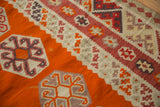 Bright tangerine orange field showcasing dark raspberry pinwheel and starburst Kilim designs.