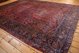 Intricate navy blue floral border meeting a dense dusty raspberry red Sarouk field.