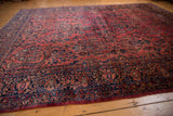 Sarouk rug border detail with curvilinear navy blue and dusty raspberry floral motifs.