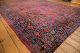 Vintage Persian Sarouk carpet corner: intricate navy border, dusty raspberry floral field.