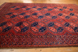 Hand-knotted Ersari carpet's brick red and navy medallions, featuring germinating plant motifs.