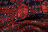 Textured vintage Ersari rug pile with deep red, navy, and cobalt geometric plant motifs.