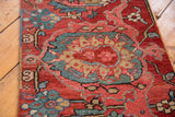 Hand-knotted antique Serapi runner's rich cherry red, teal, and ivory floral palmette detail.
